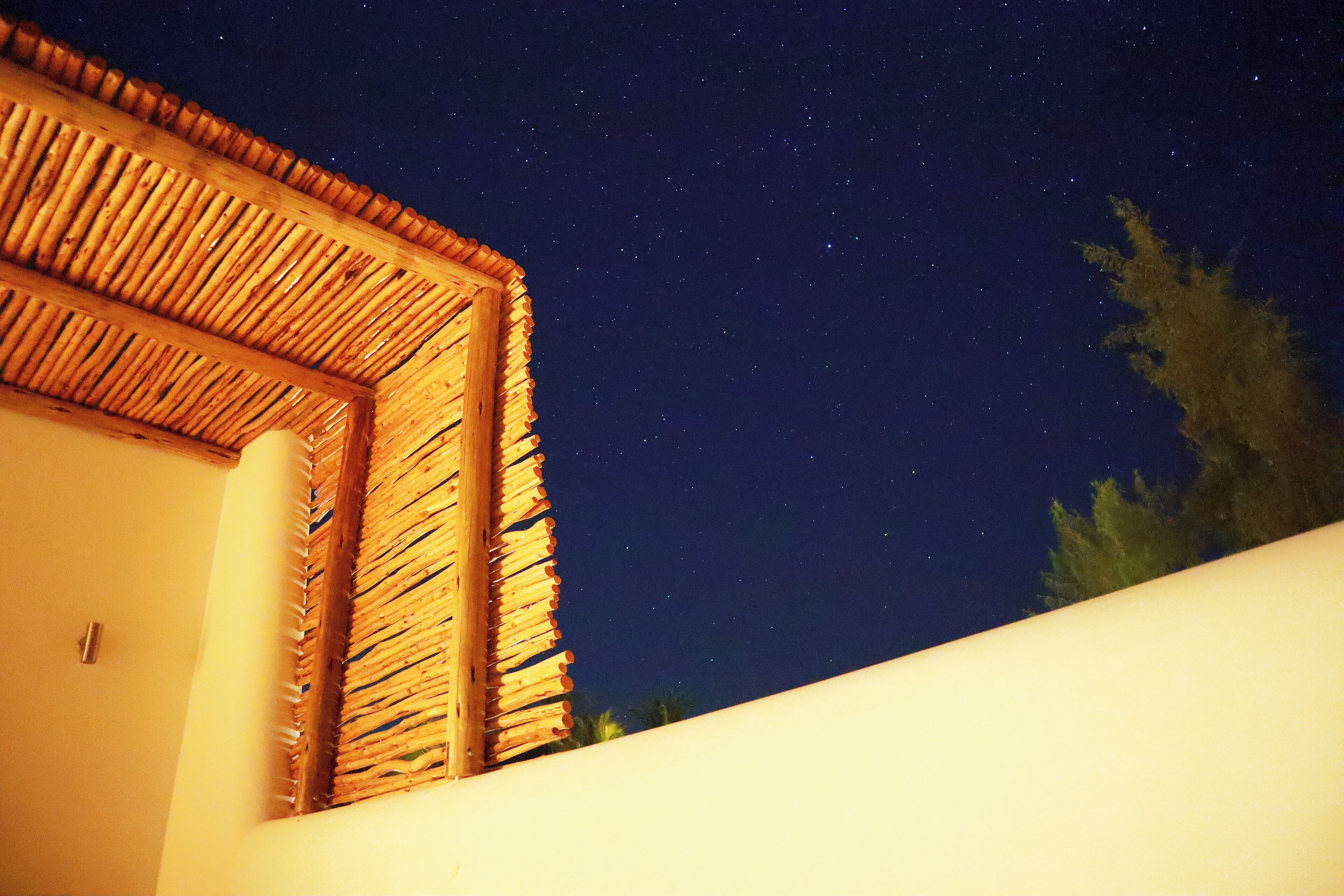 Cielo nocturno con estrellas visibles a través de una estructura de madera.