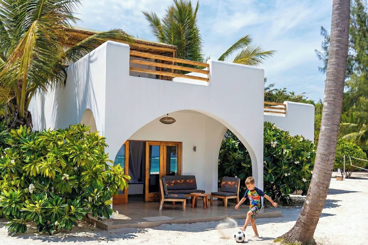 Una casa davant de la platja amb terrassa coberta, mobiliari exterior i vistes a l'oceà.