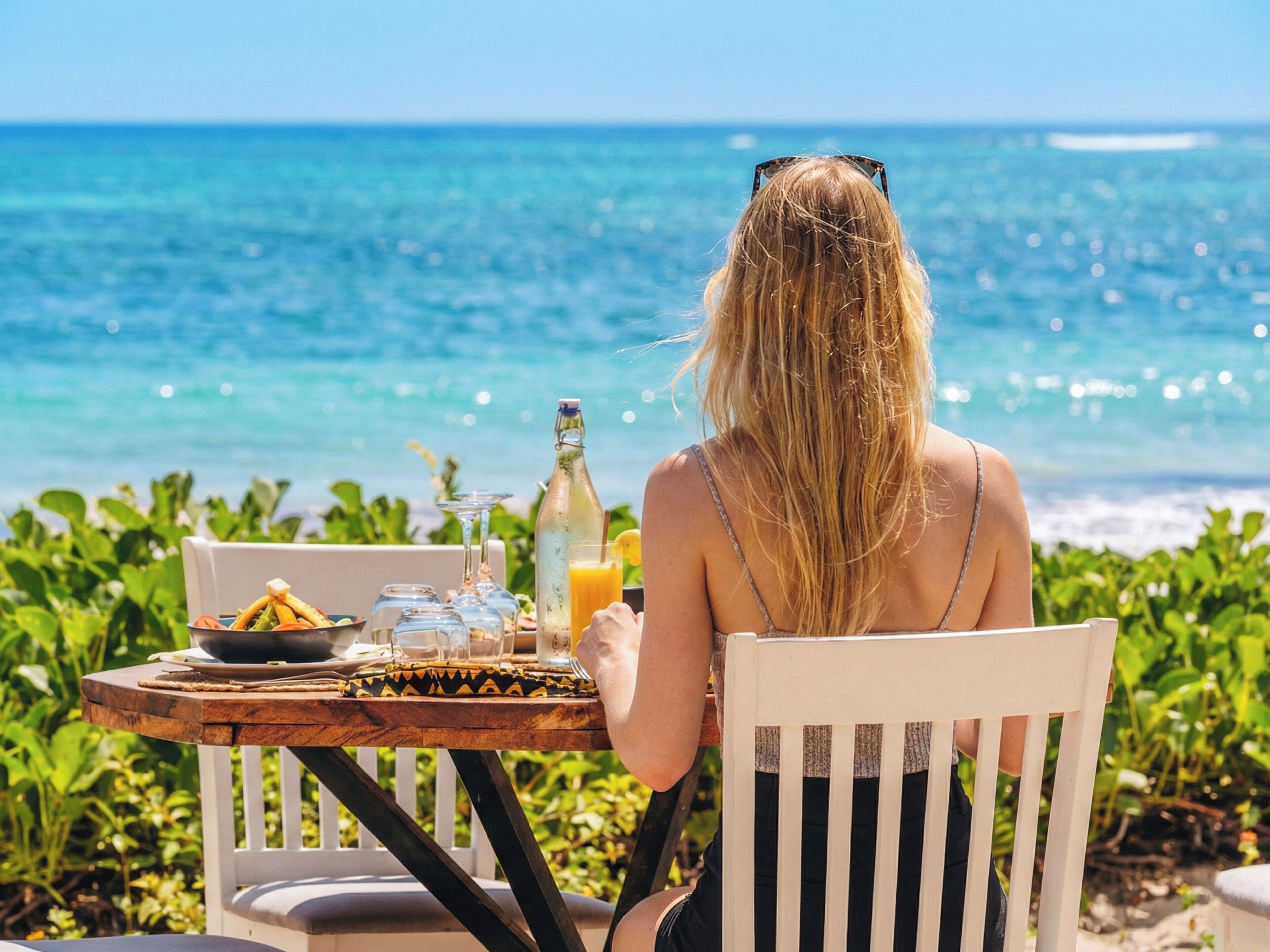 A person sitting at a table with a view of the ocean.