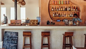 A bar area with wooden stools, a chalkboard menu, and a variety of bottles on shelves. - Kijani Beach Villas (Bwejuu)
