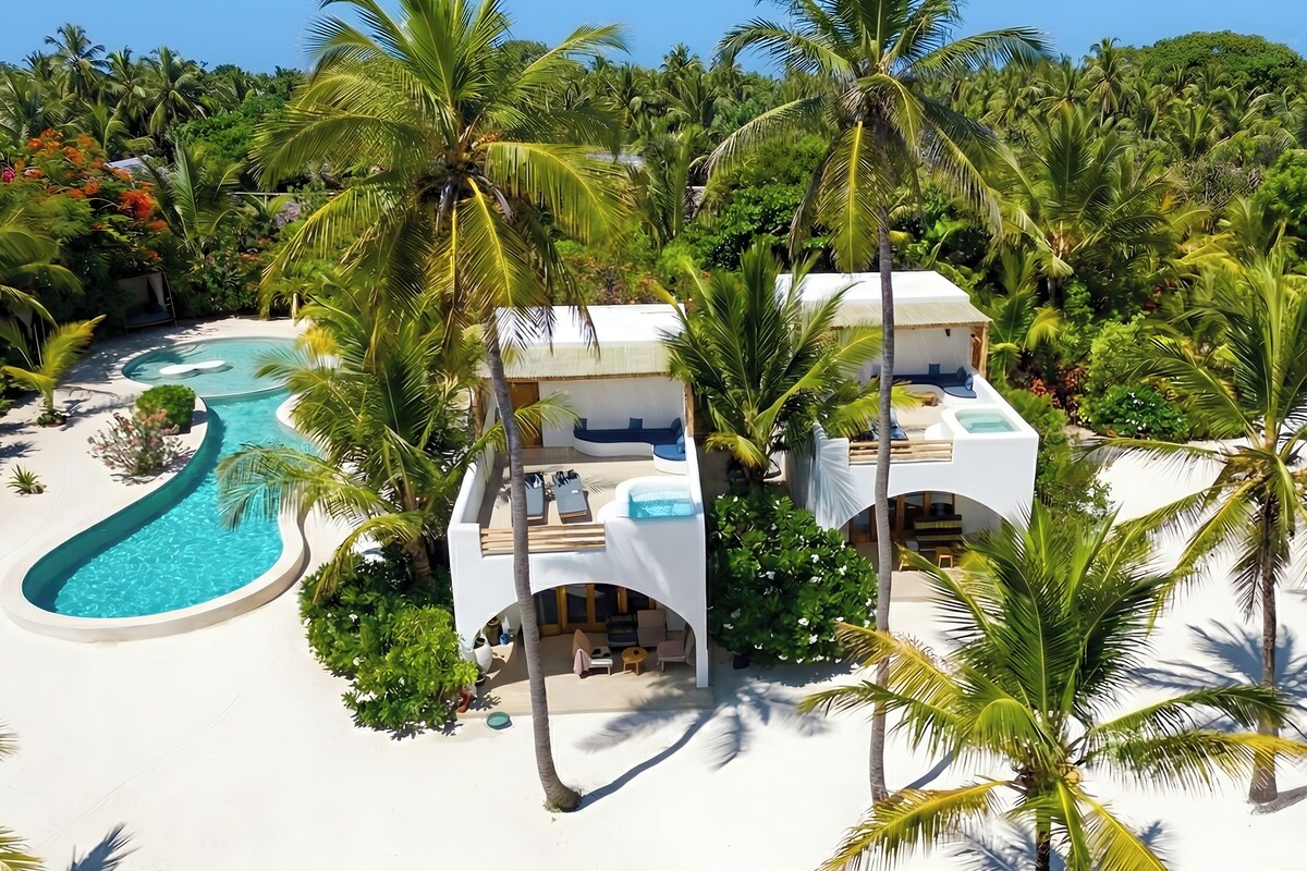 A resort with a pool, multiple rooms, and palm trees.