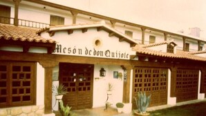 A building with a sign reading "Mesón de don Quijote". It features a traditional architectural style with wooden doors and windows, and potted plants in front. - Meson Don Quijote (Mota del Cuervo)