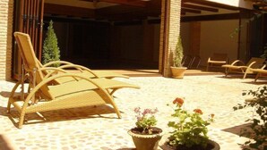 A covered outdoor seating area with wicker chairs and potted plants. - Meson Don Quijote (Mota del Cuervo)