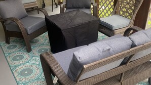 A patio area with wicker furniture, including a sofa and chairs, a small table, and a blue grill. - BonVoyage-Sleep&Sail-OvernightLayovers-Sleeps 8 Near Airport-Cruise Ports (Long Beach)