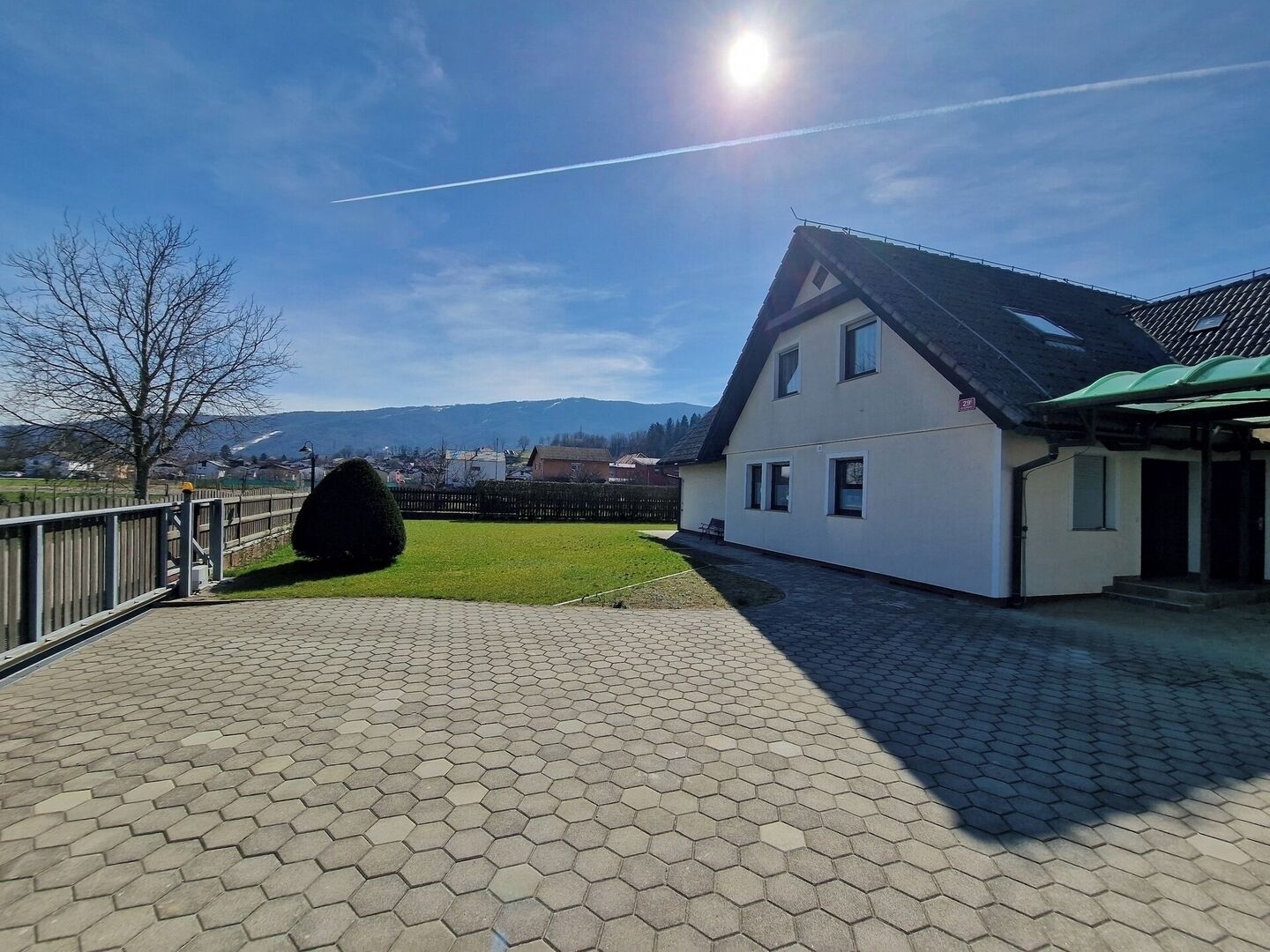 A two-story house with a paved driveway and a fenced yard.