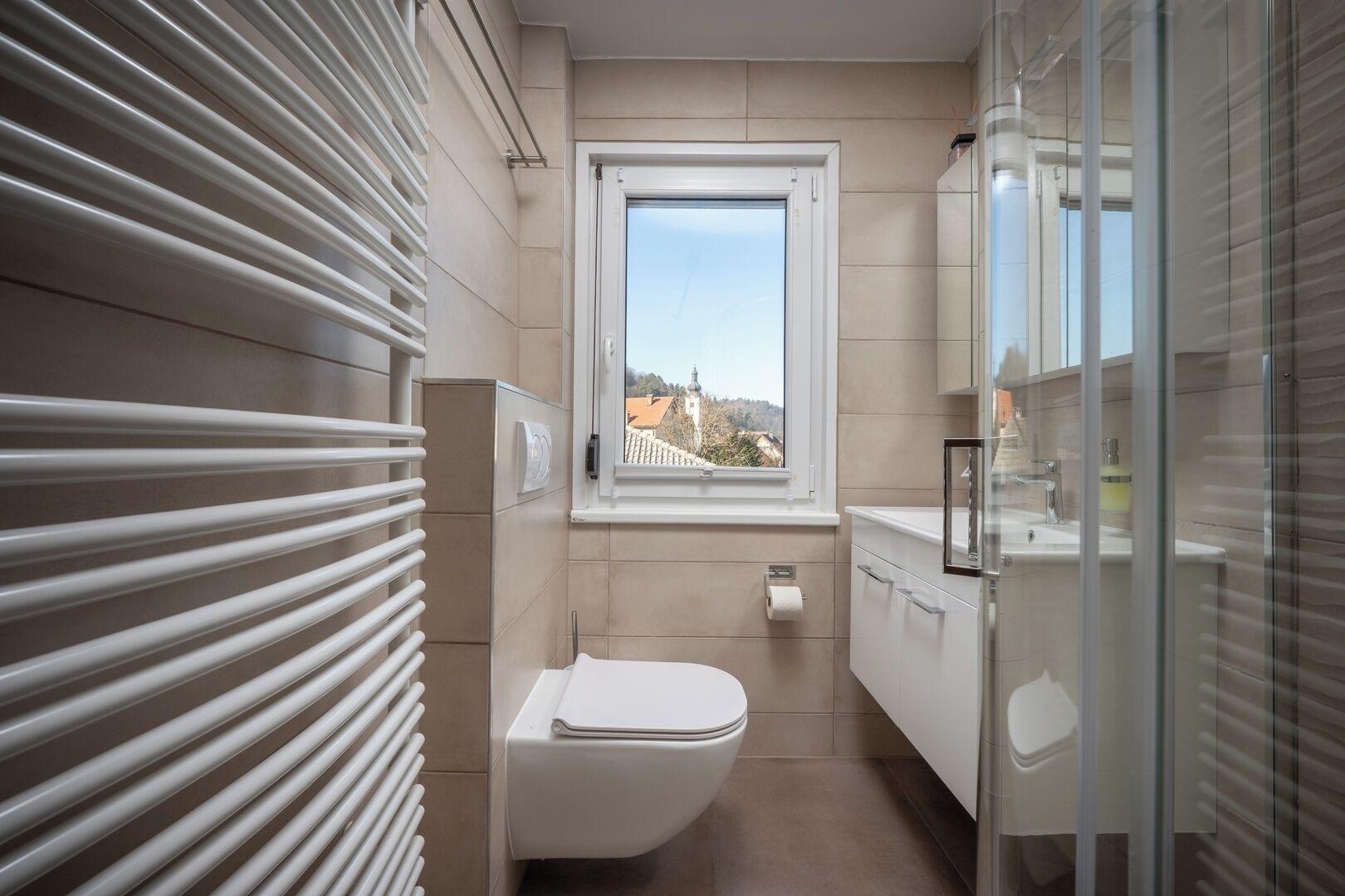 A bathroom with a toilet, a window, and a glass shower enclosure.