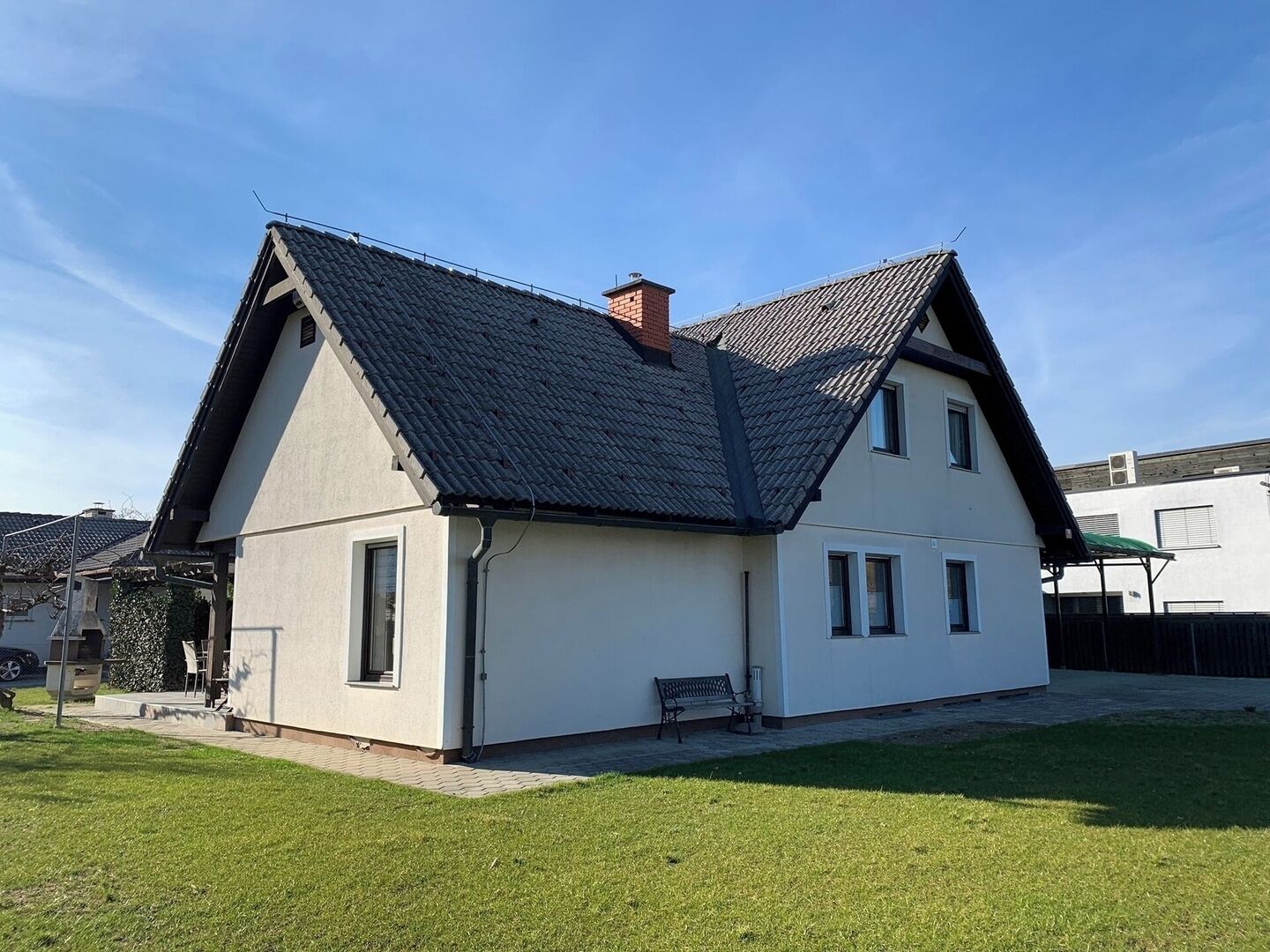 Une maison à deux étages, dotée d’un toit en pente, d’une cheminée et d’un petit porche à l’avant.