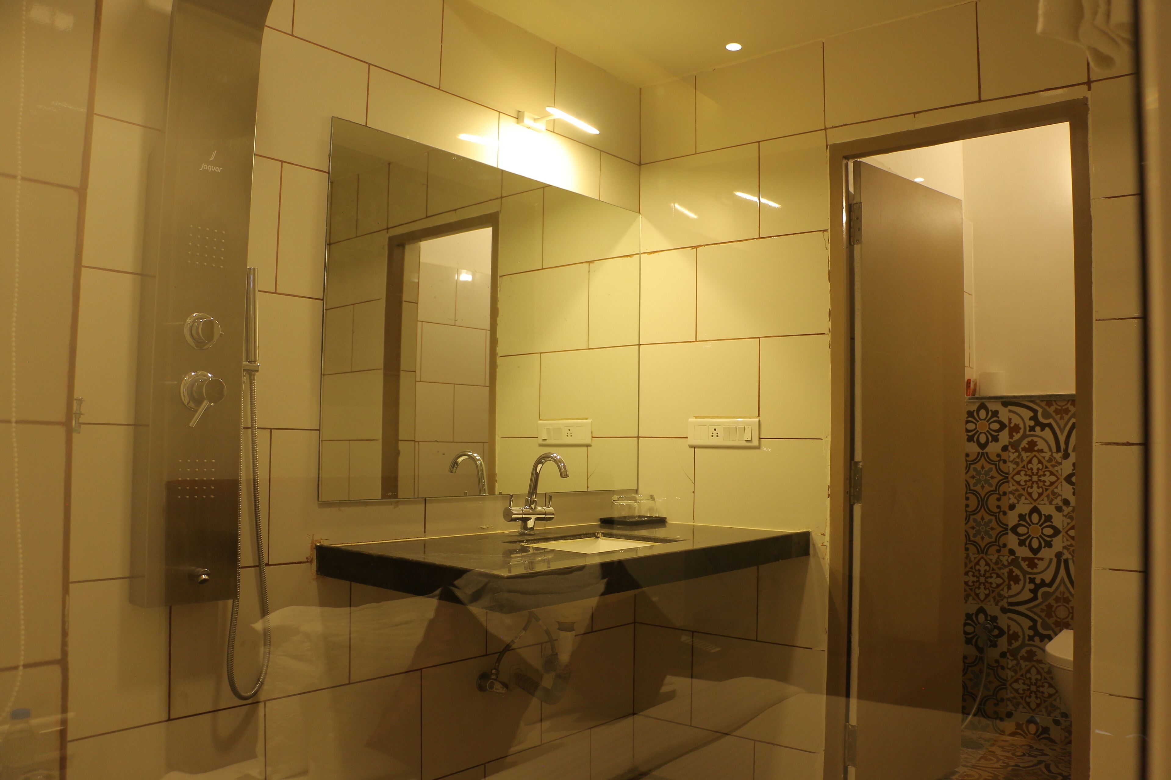 Ein modernes Badezimmer mit einer gläsernen Duschkabine, einem Waschbecken mit Spiegel und einer Wand mit Fliesern.