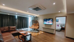 A modern living room with a leather sofa, a hanging chair, a TV, and a bed in the background. - Tulip Arena Hotel Club Event By SGL (Raipur)