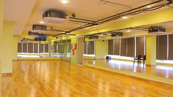 Una habitación amplia con piso de madera pulida, ventanas grandes y paredes espejadas.