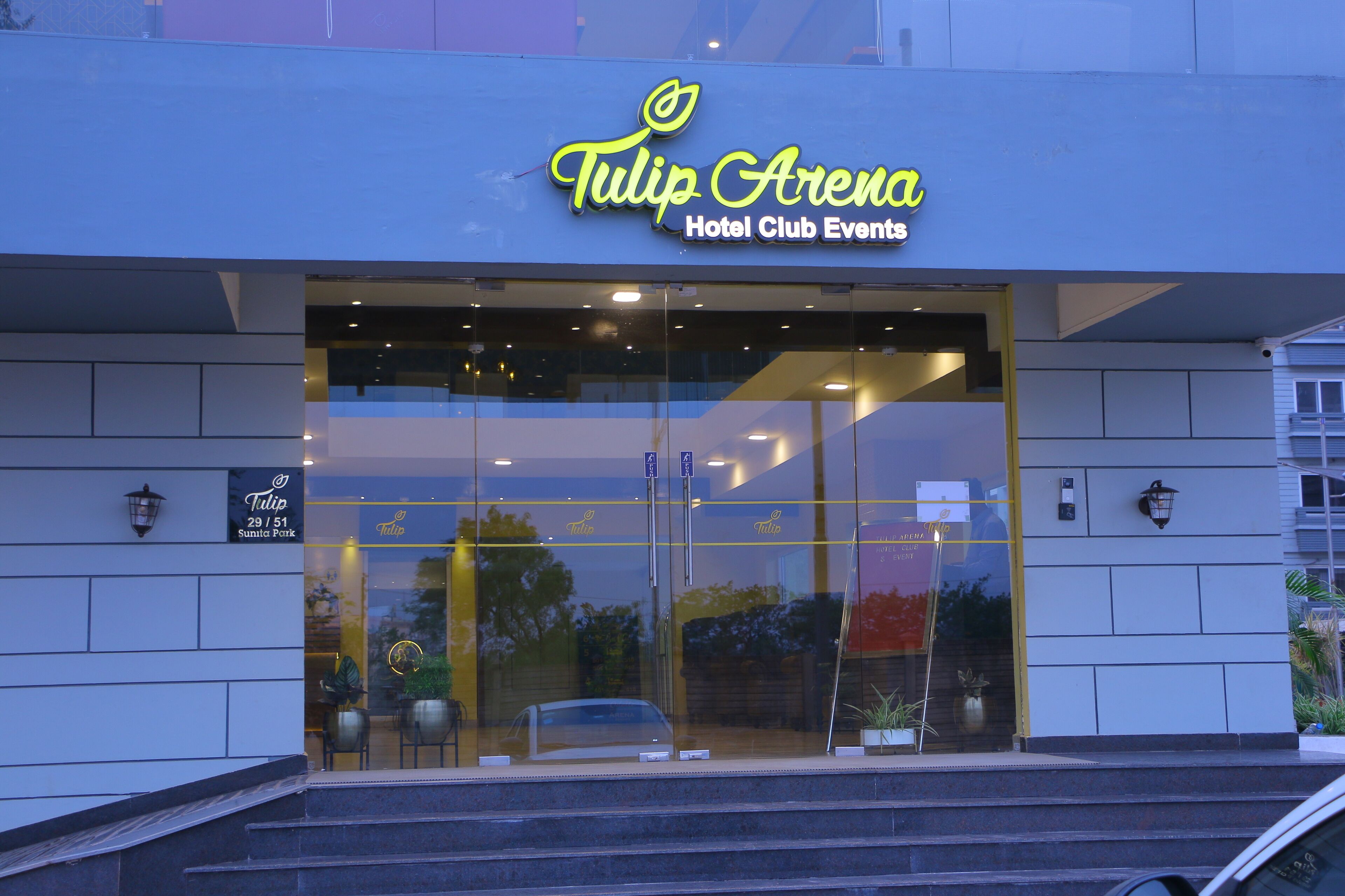 The exterior of the Tulip Arena Hotel Club Events with a modern design, large glass entrance, and visible signage.
