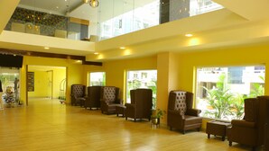 A spacious lobby with multiple seating areas, a staircase, and large windows providing views of the outside. - Tulip Arena Hotel Club Event By SGL (Raipur)