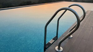 A swimming pool with metal railings and a view of the sunset over a cityscape. - Tulip Arena Hotel Club Event By SGL (Raipur)