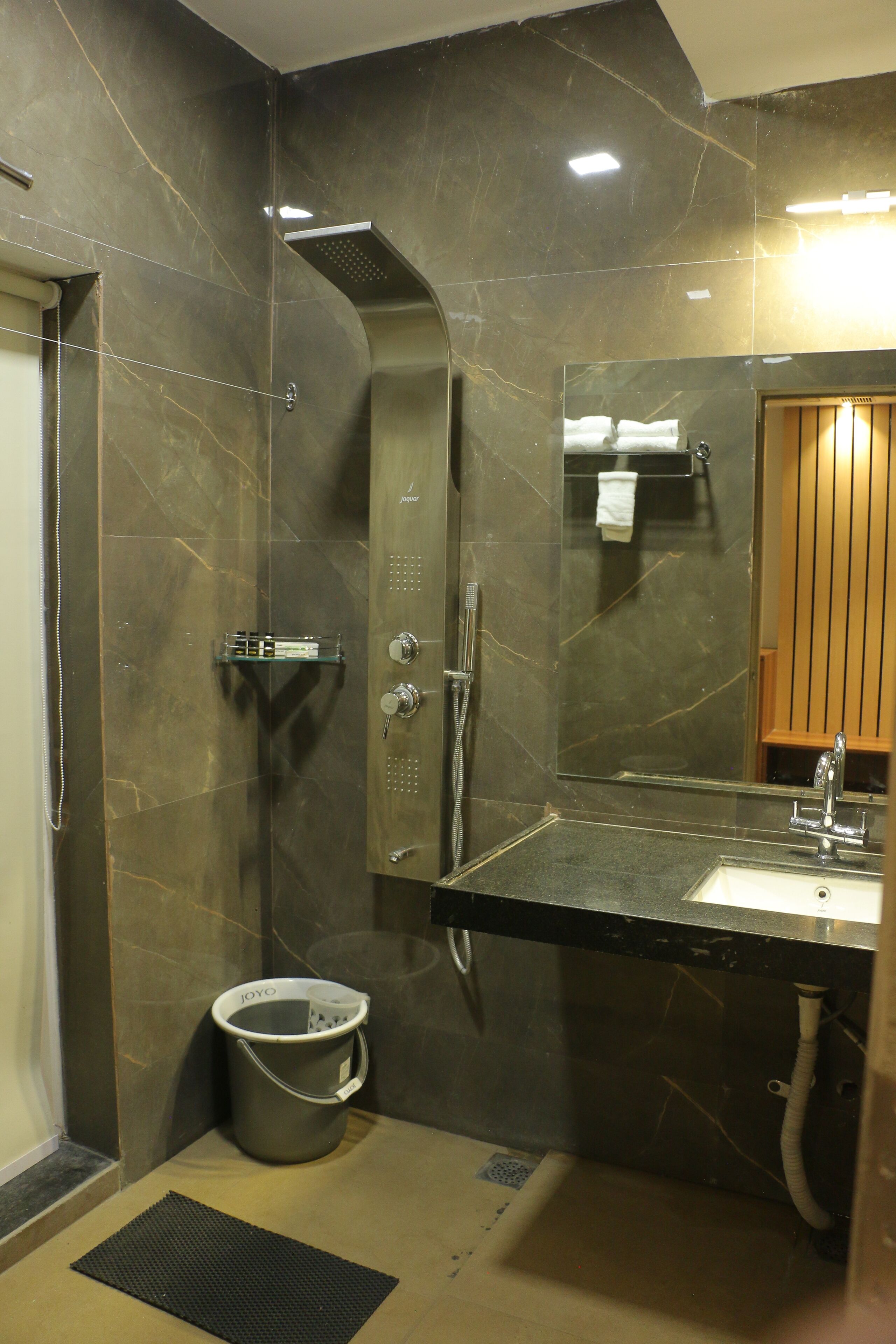 A modern bathroom with a curved shower, a glass shower enclosure, a sink with a mirror, and a towel rack.