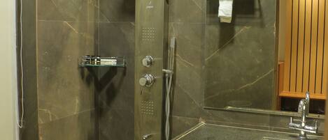 Une salle de bain moderne avec une douche à parois incurvées, un pare-douche en verre, un lavabo avec un miroir et un porte-serviettes.