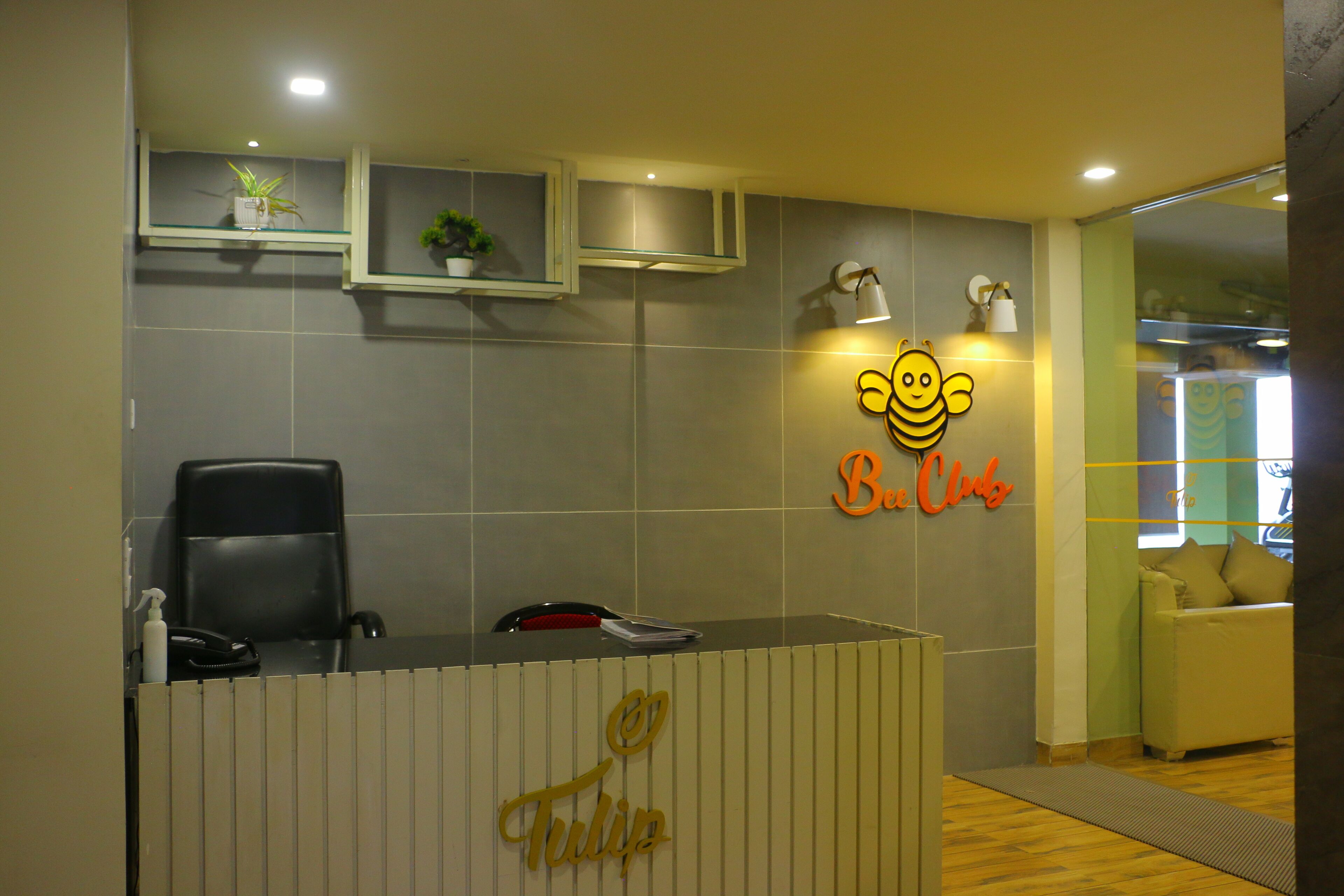 A reception desk with a sign that reads "Tulip" and a neon sign with a bee and the text "B. Club".