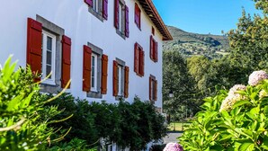 Un edificio bianco con persiane rosse e una montagna sullo sfondo.
