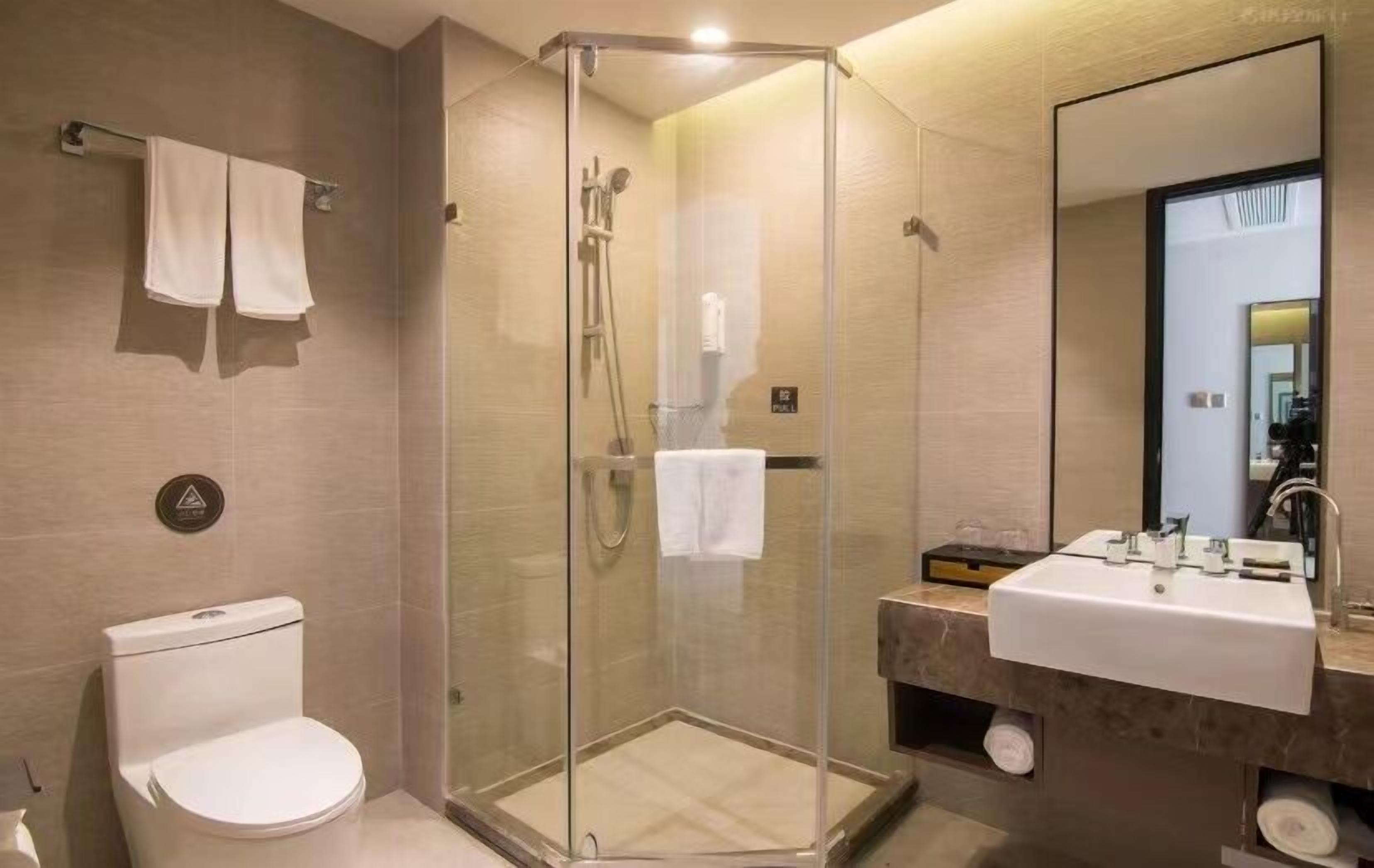 A modern bathroom with a glass-enclosed shower, a toilet, and a sink with a mirror.