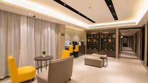 A modern hotel lobby with a seating area, a reception desk, and a bookshelf. - Home Inns Collection Hotel (Shanghai)