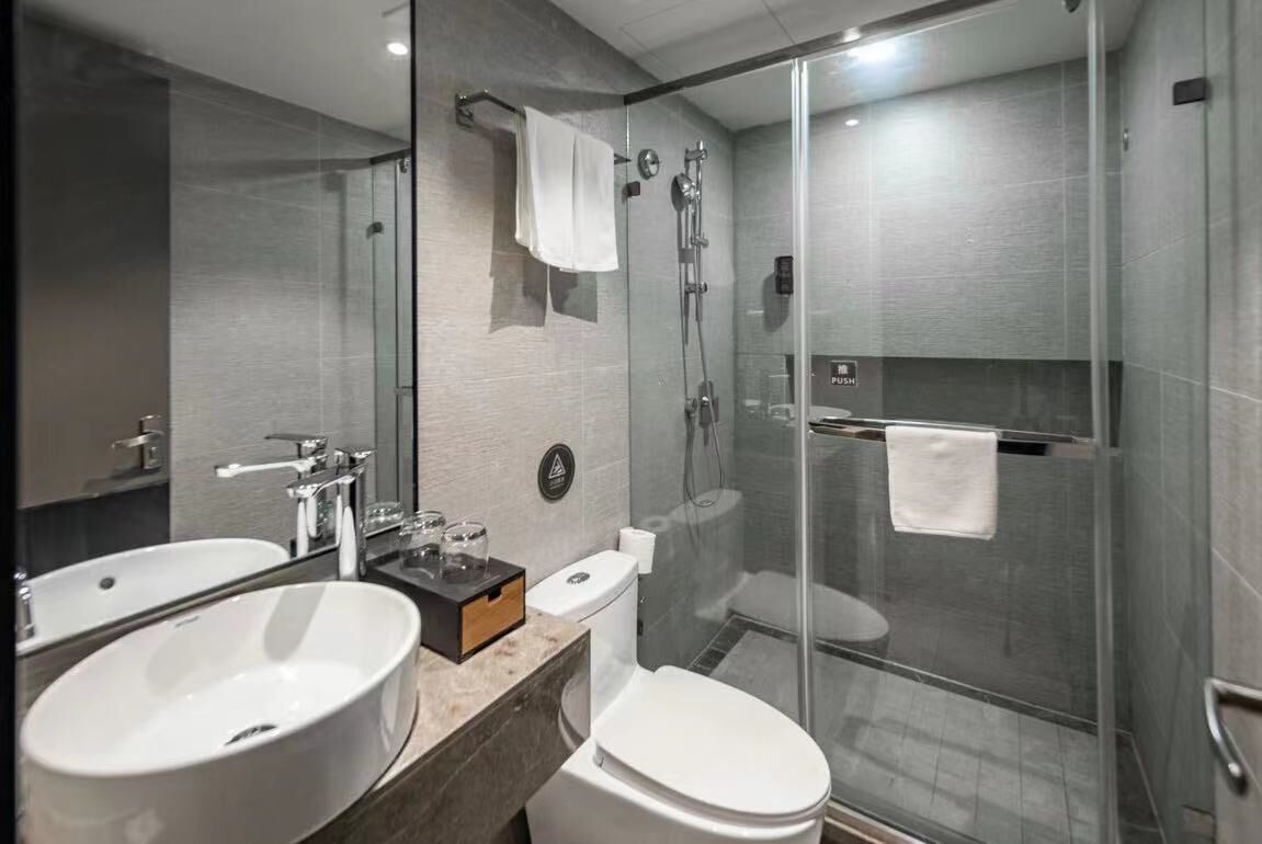 A modern bathroom with two sinks, a toilet, a glass shower enclosure, and a towel rack.