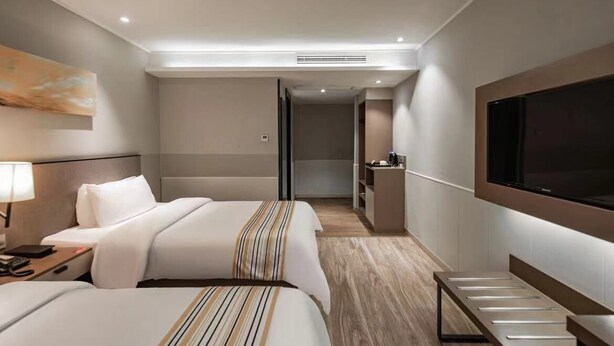 A hotel room with two beds, a TV, a desk, and a bathroom visible through an open door. - Home Inns Collection Hotel (Shanghai)