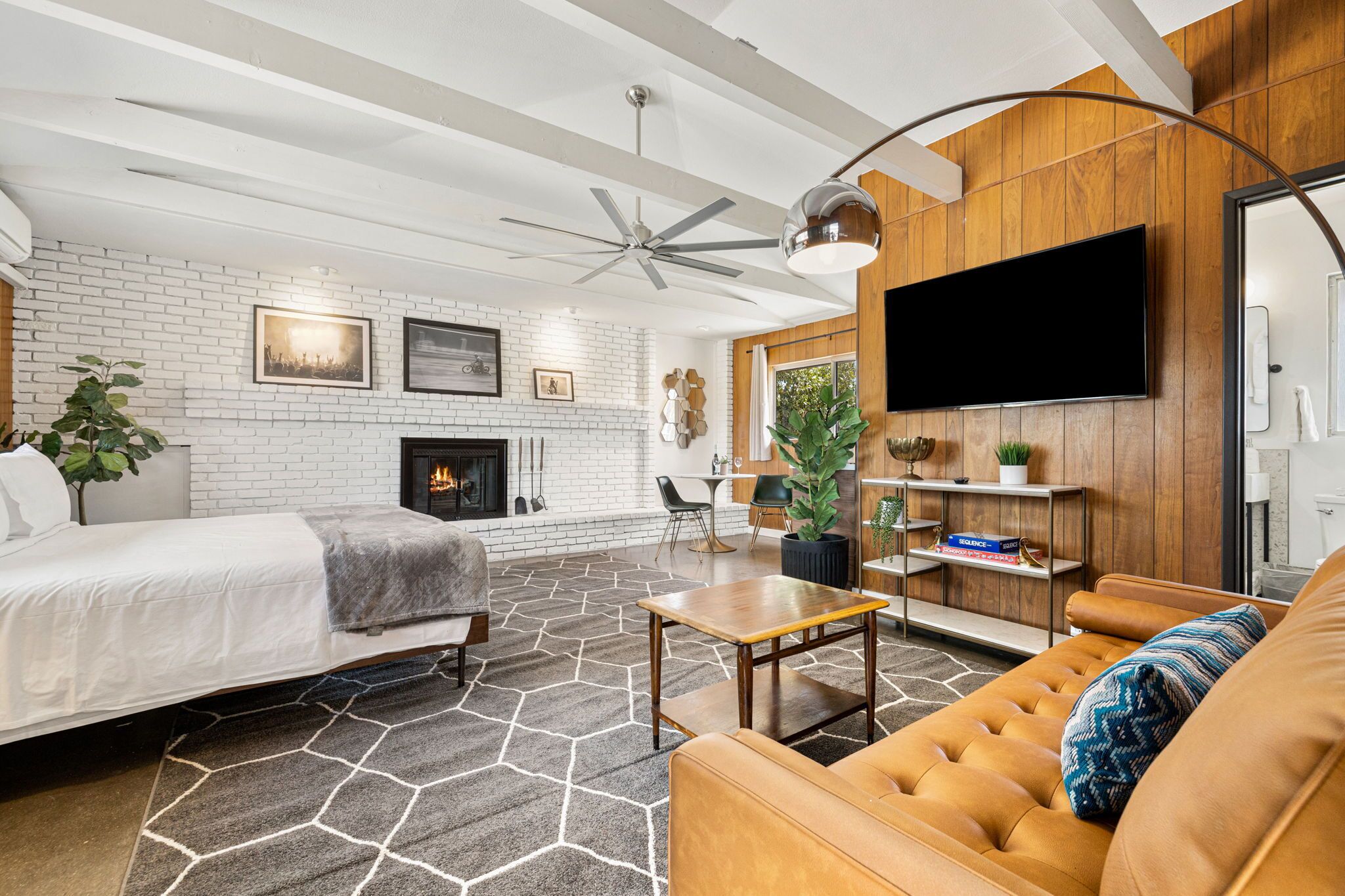 A modern living room with a fireplace, a sofa, a coffee table, and a TV mounted on the wall.