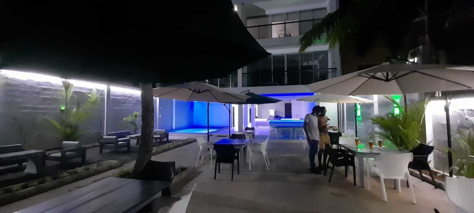 An outdoor dining area with tables and chairs, umbrellas, and potted plants.