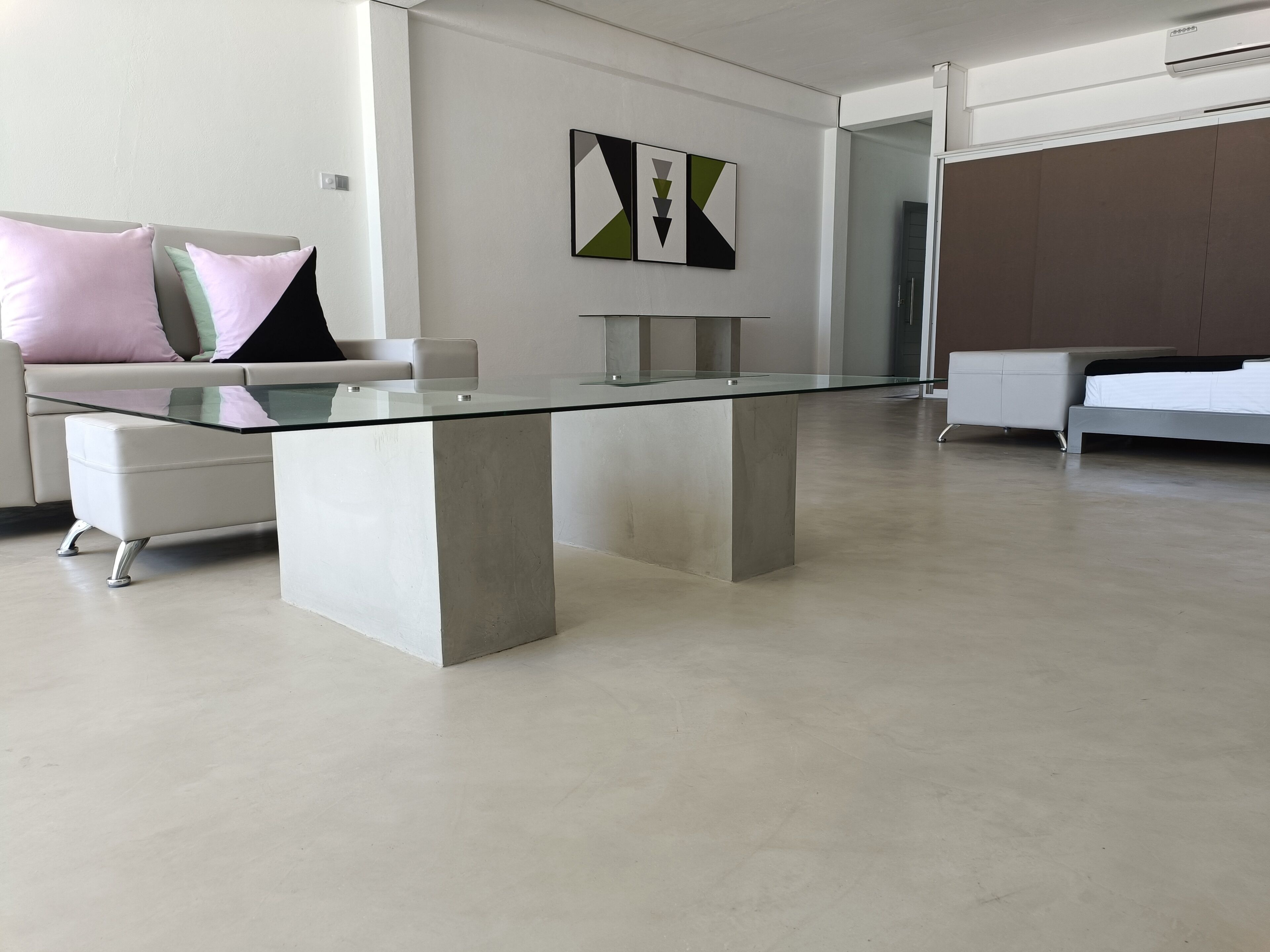 Un espace de bureau moderne avec une table à plateau de verre, des canapés blancs et un décor minimaliste.