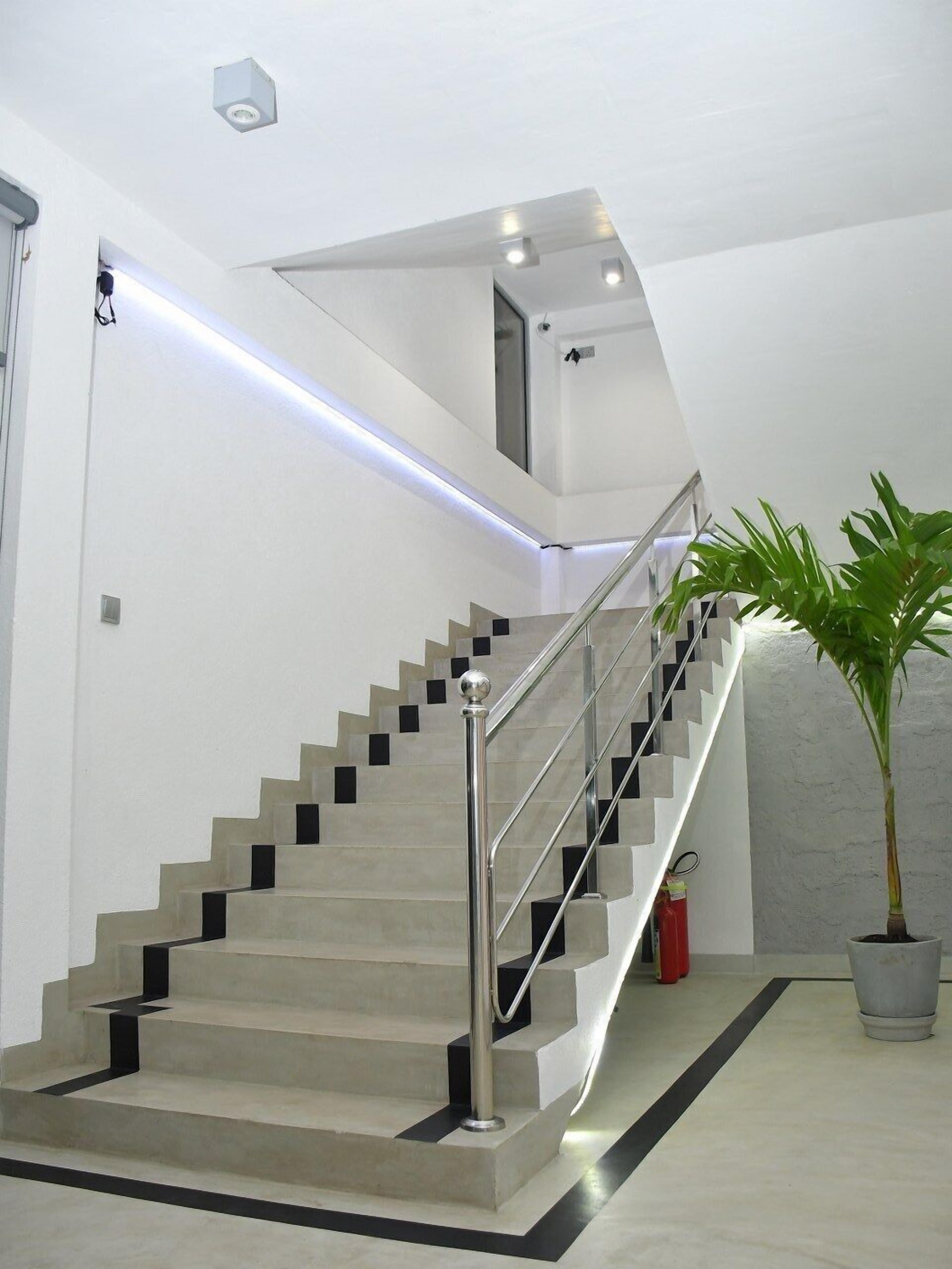 A modern staircase with a metal railing, a potted plant, and a fire extinguisher.