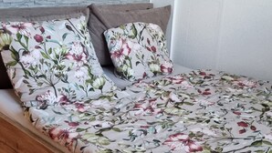 A bed with floral bedding, a wooden frame, and a brick wall behind it. - Modern Eingerichtete 3-zi.-ferienwohnung zu Vermieten (Löffingen)