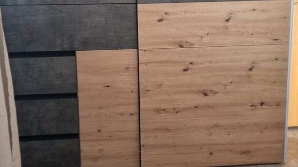 A bedroom with a bed, a wooden headboard, and a grey and brown wall panel. - Modern Eingerichtete 3-zi.-ferienwohnung zu Vermieten (Löffingen)