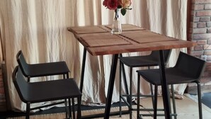 A wooden table with a vase of flowers, two black chairs, and a beige curtain in the background. - Modern Eingerichtete 3-zi.-ferienwohnung zu Vermieten (Löffingen)