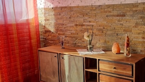 A room with a brick wall, a wooden cabinet with drawers, a glass vase with flowers, and a decorative object on the cabinet. - Modern Eingerichtete 3-zi.-ferienwohnung zu Vermieten (Löffingen)