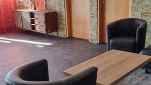 A modern room with a wooden coffee table, black armchairs, and a desk with drawers. - Modern Eingerichtete 3-zi.-ferienwohnung zu Vermieten (Löffingen)