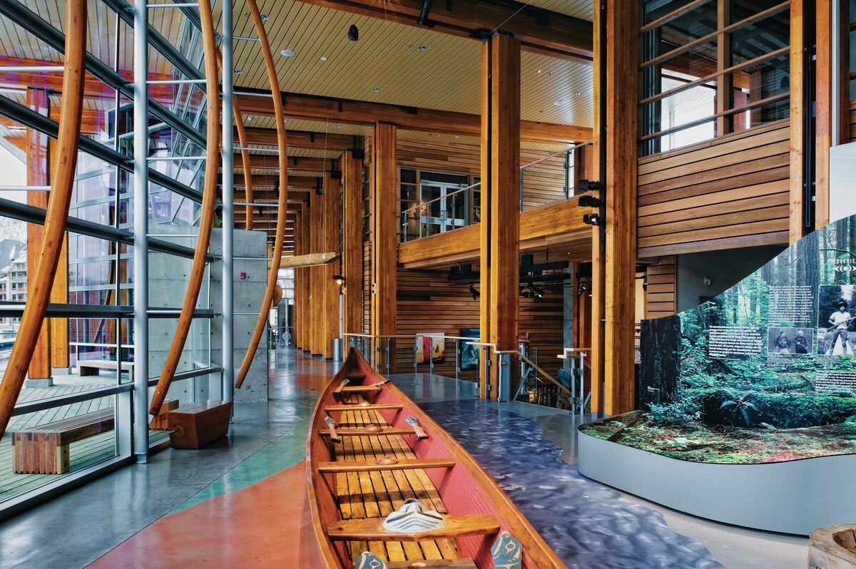 Un intérieur moderne avec des poutres en bois, des murs en verre et une exposition de bateaux.