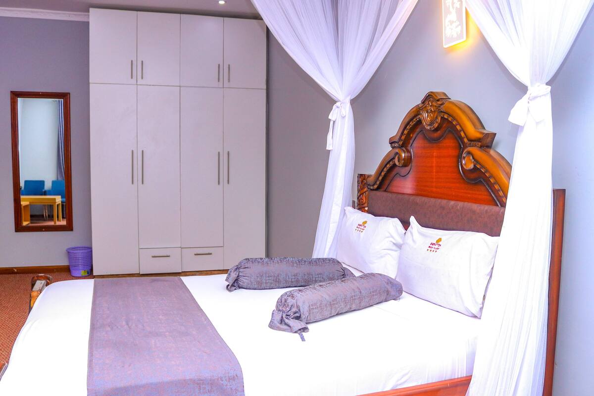 Une chambre à coucher avec un lit, une tête de lit en bois, une armoire et un miroir.