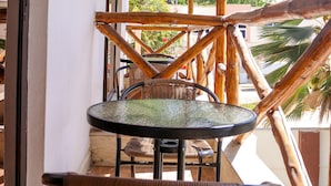 A balcony with a wicker chair, a small round table, and a metal railing. - SHERATTON BEACH VILLAGIO HOTEL (Mombasa)