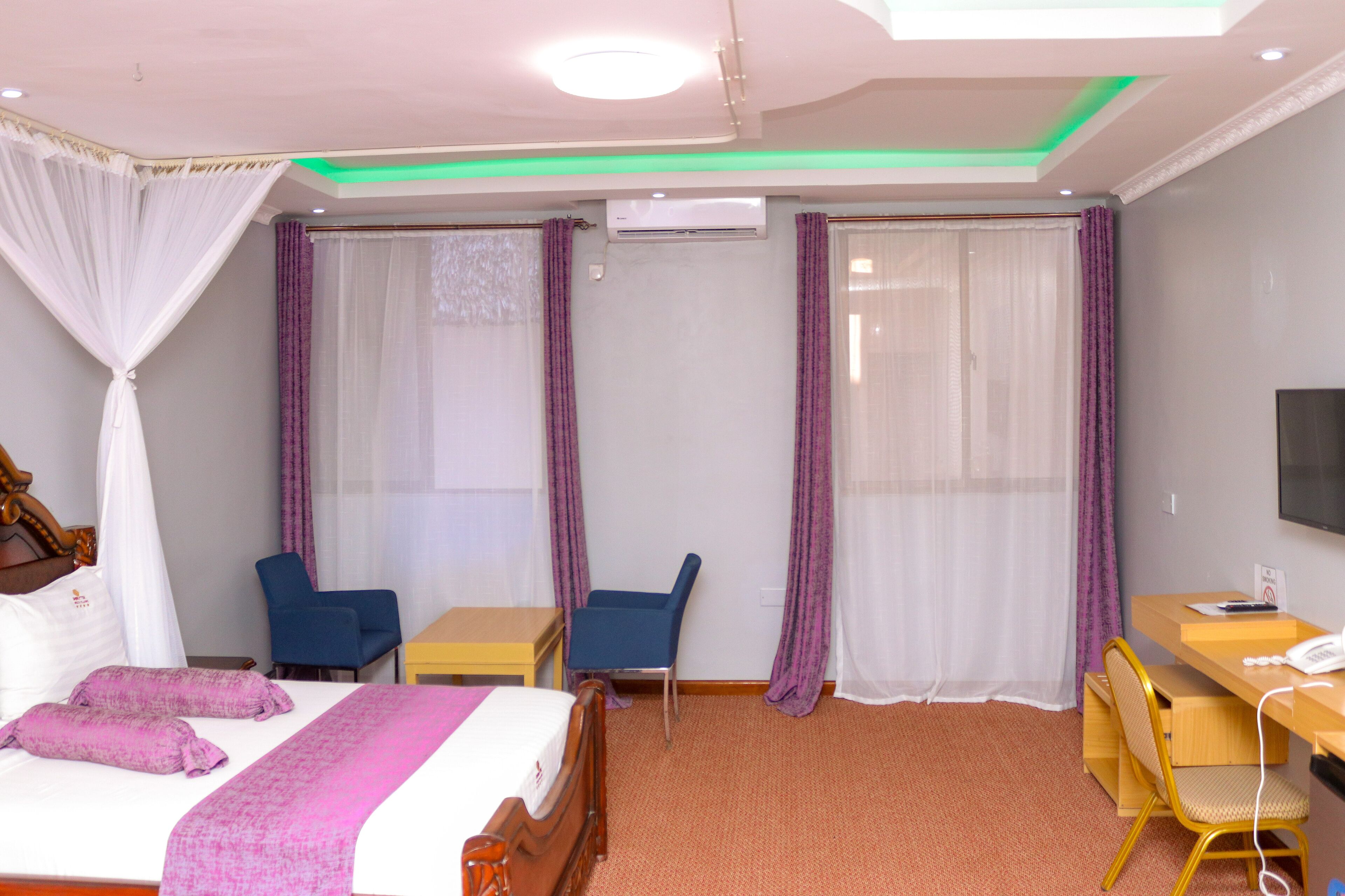 A hotel room with a bed, a desk, a chair, and a television.