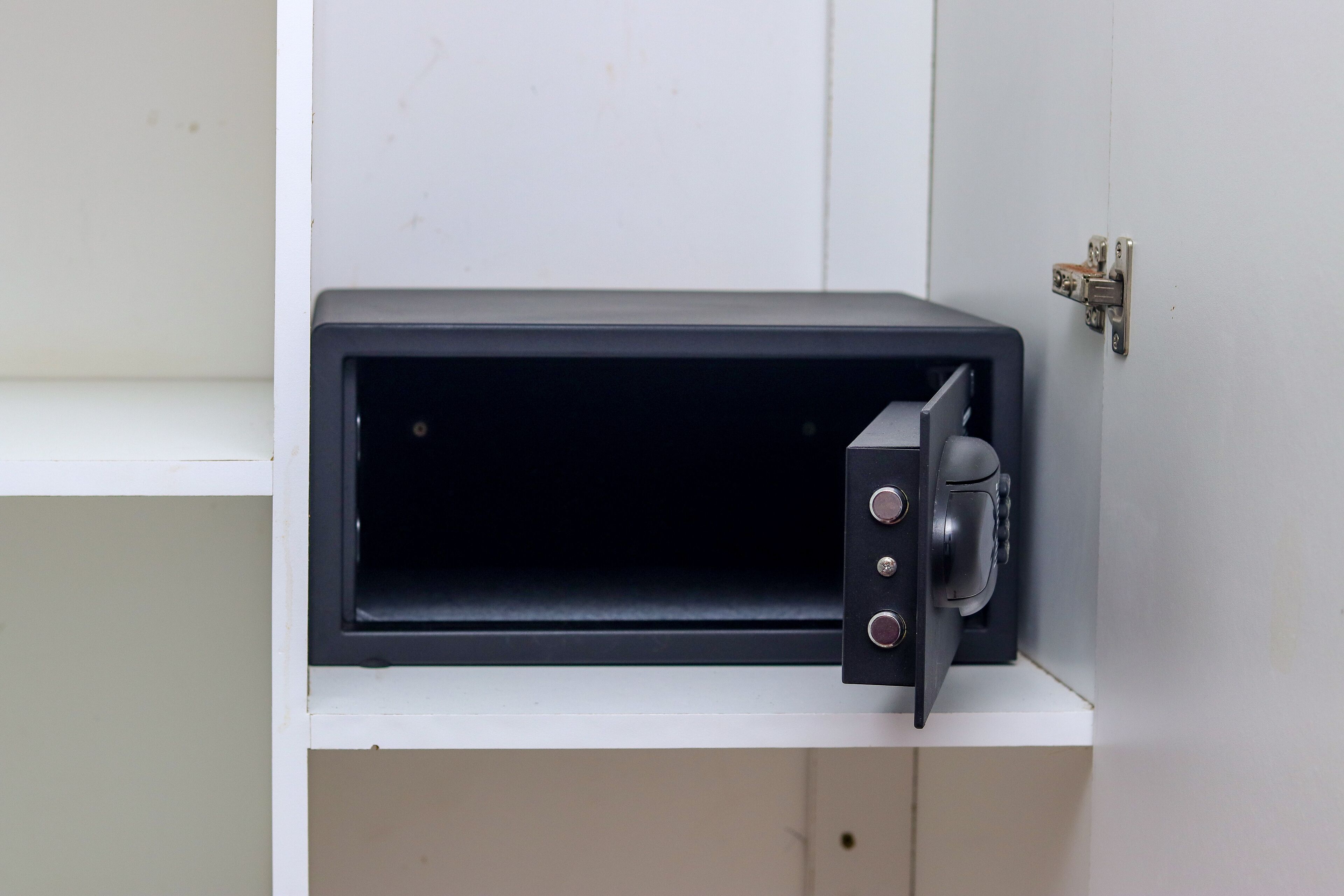 Forno de microondas fixado em um armário branco com fecho metálico.
