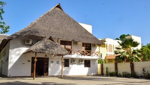 A building with a thatched roof and a balcony. - SHERATTON BEACH VILLAGIO HOTEL (Mombasa)
