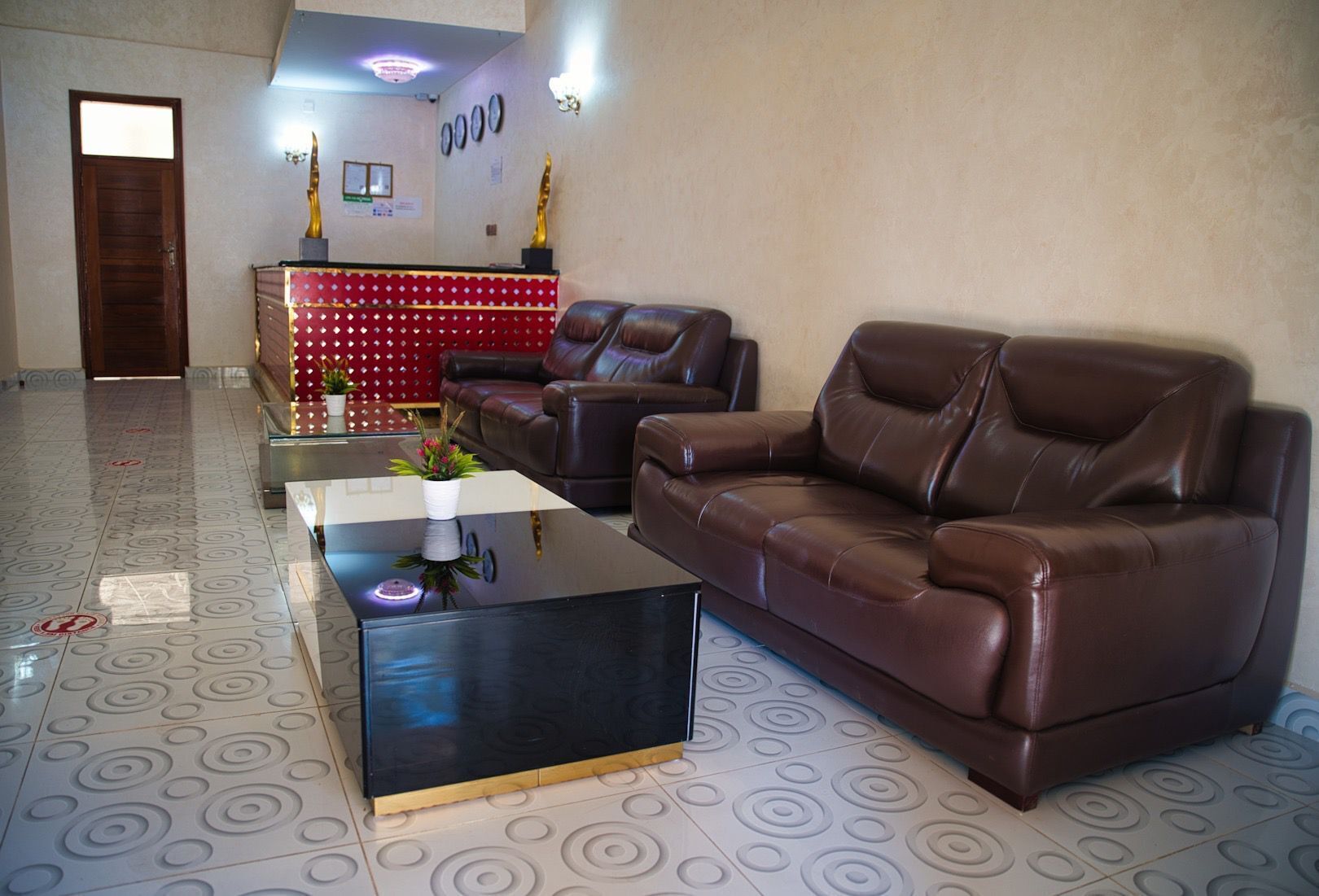 Ein geräumiger Wohnbereich mit einer braunen Ledersofa, einem schwarzen Couchtisch mit weißer Vase und einem roten, gemusterten Schrank.