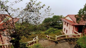A traditional building with a red roof, a stone pathway, and a white railing.