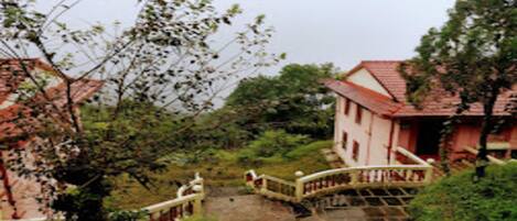 A traditional building with a red roof, a stone pathway, and a white railing.