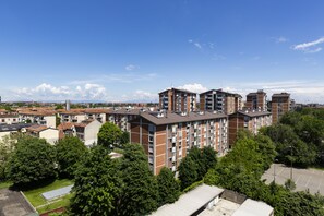 A multi-story residential building with a brick facade, multiple balconies, and a parking area in the foreground. - notaMI - House San Cristoforo M4 (Milan)
