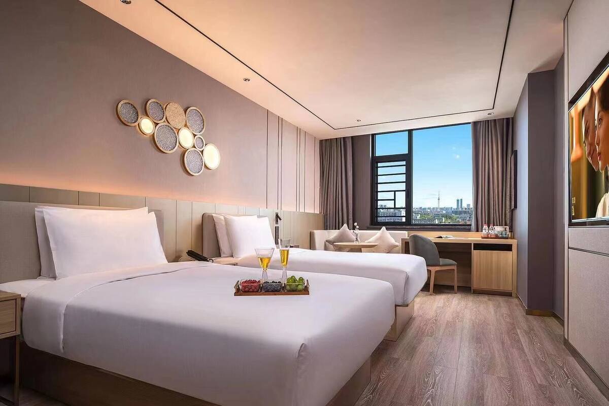 A modern hotel room with a large bed, a desk, and a view of the city.