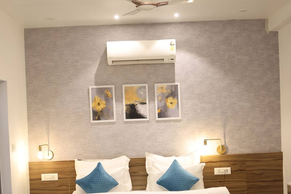 A modern bedroom with a wooden bed, a ceiling fan, wall-mounted air conditioning, and framed artwork.