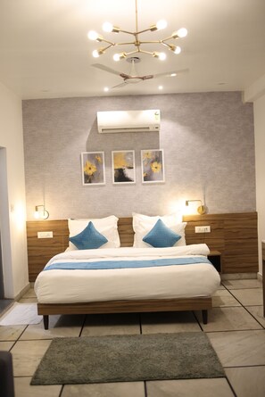 A modern bedroom with a wooden bed, a ceiling fan, wall-mounted air conditioning, and framed artwork.