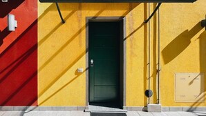 Un bâtiment avec une porte verte, des murs jaunes et une partie rouge sur le côté gauche.