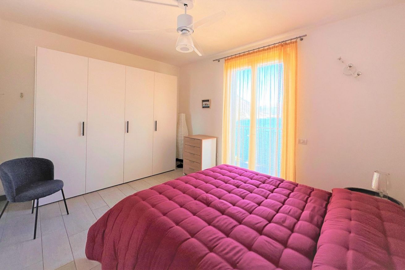 Een slaapkamer met een bed, een stoel, een kledingkast, een bureau en een raam met gordijnen.