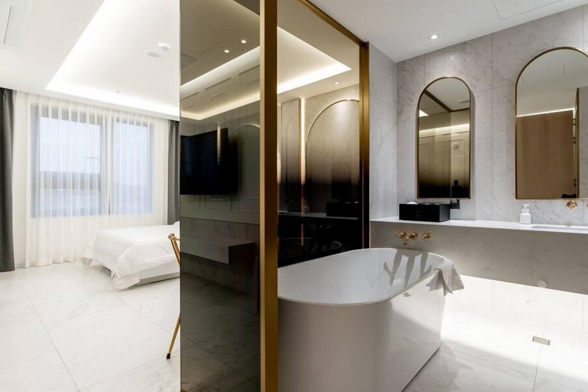 Un baño de hotel moderno con una bañera independiente, un espejo grande y un tocador con lavabo.